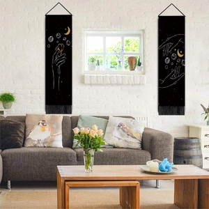 Detail of minimalist black tapestry with white line art moon and stars hung over a sofa