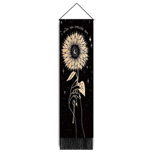 Detail of bohemian wall tapestry featuring sunflower and moon art with black tassels