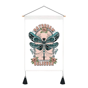 Detail of dragonfly tapestry with wooden hanger, tassels, and Daydream Believer text