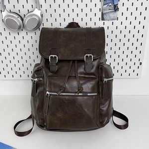 Vintage brown leather backpack with buckle straps and drawstring closure on a white desk