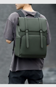 Detail view of a large dark green waterproof travel backpack worn by a male model