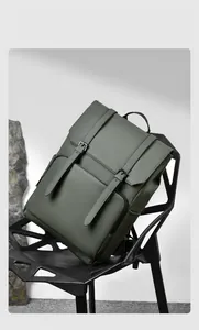 Modern olive green leather backpack with flap closure and dual buckles on a black chair