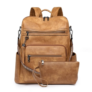 Detail of vintage brown leather backpack with woven ethnic strap and fringe tassel charm