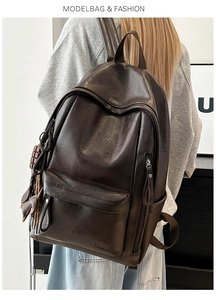 Detalle de mochila de cuero suave marrón oscuro con logo de marca y accesorios