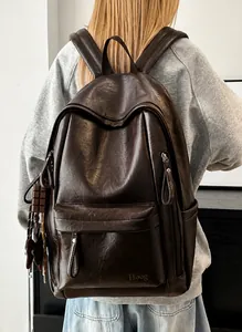 Detalle de mochila de cuero marrón oscuro con logo Hoog y textura de grano de calidad