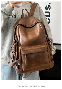 Detalle de mochila de cuero marrón vintage con textura fina y colgante de perro lindo