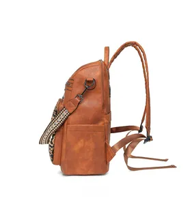 Side view of caramel faux leather backpack with leopard print pocket and woven strap