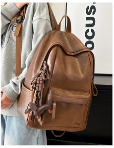 Detalle de mochila de cuero marrón oscuro con colgantes de chocolate y perro salchicha