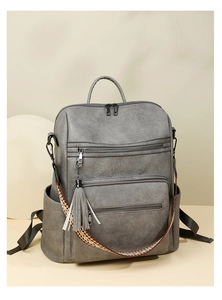 Detail of grey multi-pocket backpack with ethnic style strap and tassel charm