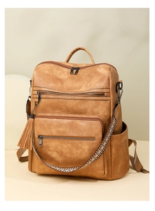 Detail view of brown vintage leopard backpack with ethnic woven strap and tassel charm