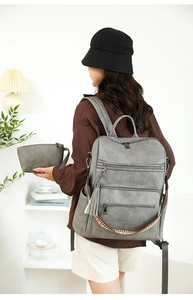 Grey pebbled leather backpack with tassel detail and colorful ethnic woven shoulder strap
