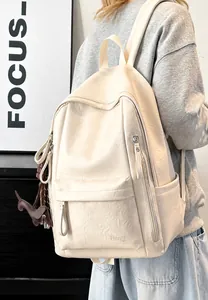 Detalle de mochila de cuero PU crema suave con logo Hoog y colgante de perrito