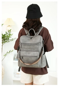 Detail view of grey faux leather backpack with multiple pockets and bohemian strap