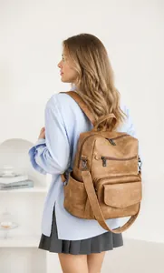Vista de detalle de una mochila vintage de cuero sintético marrón usada por una modelo