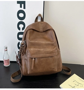 Detailed close-up of dark brown soft PU leather backpack with decorative plush charms