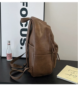 Side view of dark brown faux leather backpack with side pockets and smooth zippers
