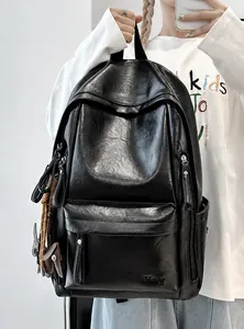 Detalle de mochila de cuero suave negro con logo grabado y colgante de conejo marrón
