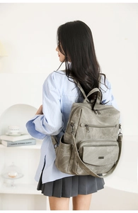 Detalle de una mochila vintage de cuero sintético gris con varios bolsillos con cremallera