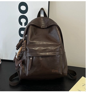 Detail view of dark brown PU leather backpack with Hoog logo and decorative charms