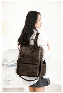 Detalle de mochila vintage marrón oscuro con múltiples cremalleras y textura mate suave