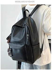 Detalle de mochila de cuero negro mate con colgante de oso y correas ajustables