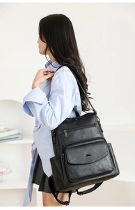 Detalle de una mochila de cuero sintético negro con varios bolsillos en un modelo