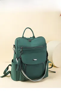 Detail view of dark green PU leather backpack with striped strap and fringe charm