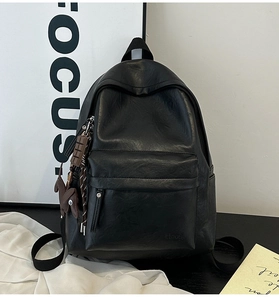 Detail view of the black soft leather backpack with cute animal charm and front pocket
