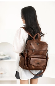 Detalle de la mochila vintage de cuero sintético marrón lucida por una modelo joven