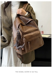 Detail of vintage brown soft leather backpack featuring Hogog logo and cute dachshund charm