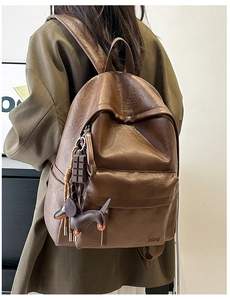 Detail of a brown leather backpack with cute chocolate and dachshund charms on the front