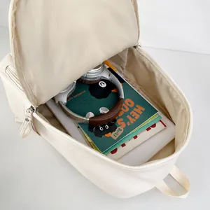 Interior espacioso de la mochila de cuero PU beige con libros y cascos mostrando capacidad