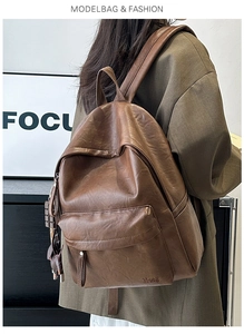 Brown faux leather backpack showing front pocket detail and embossed brand logo
