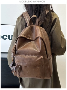 Detail of soft brown leather backpack with Hoeg logo and adjustable shoulder straps