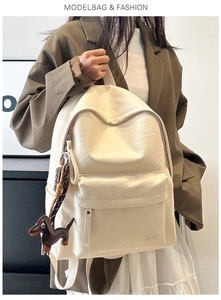 Detail of minimalist beige faux leather backpack with front pocket and dachshund charm