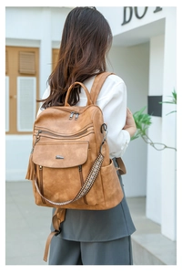 Brown PU leather backpack detail showing bohemian woven strap and decorative tassels