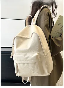Detail view of cream leather backpack with Hoor logo and large front pocket on model