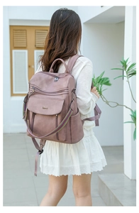Detail of dusty pink PU leather backpack featuring rainbow strap and multiple zippers