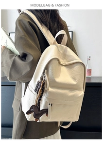 Detail view of cream backpack with soft leather texture and cute puppy keychain accessories
