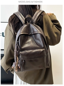 Model wearing dark brown vintage PU leather backpack with decorative chocolate pendant