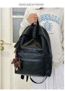 Detail of black soft leather backpack with a cute bear charm and adjustable straps