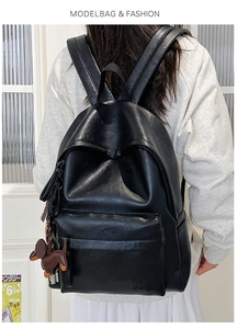 Detail of black soft leather backpack with cute dog charm pendant on model back