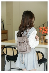 Detailed close-up of a retro taupe PU leather backpack with gold heart pendant