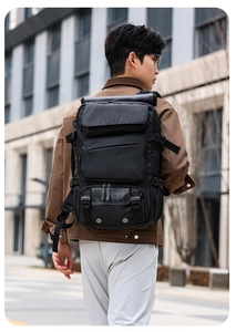 Detail of a large black tactical travel backpack with multiple zippers and side mesh pockets