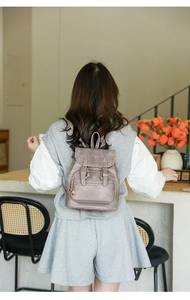 Detailed back view of a vintage taupe PU leather backpack worn by a model in a cozy cafe