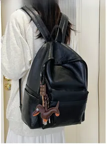 Detail of black soft PU leather backpack with cute dog charm and chocolate pendant