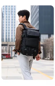 Male model wearing large black tactical travel backpack in an urban street setting