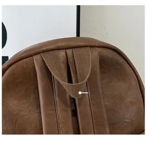 Close-up of comfortable top handle and reinforced strap stitching on brown leather backpack
