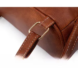Macro detail of brown leather bag with white contrast stitching and golden square buckle