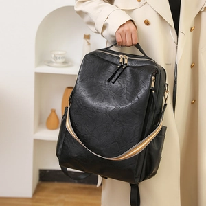 Detail eines schwarzen Kunstleder-Rucksacks mit Goldreißverschlüssen und Webriemen
